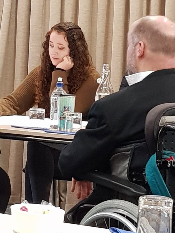 Gray at a meeting table, listening to a colleague