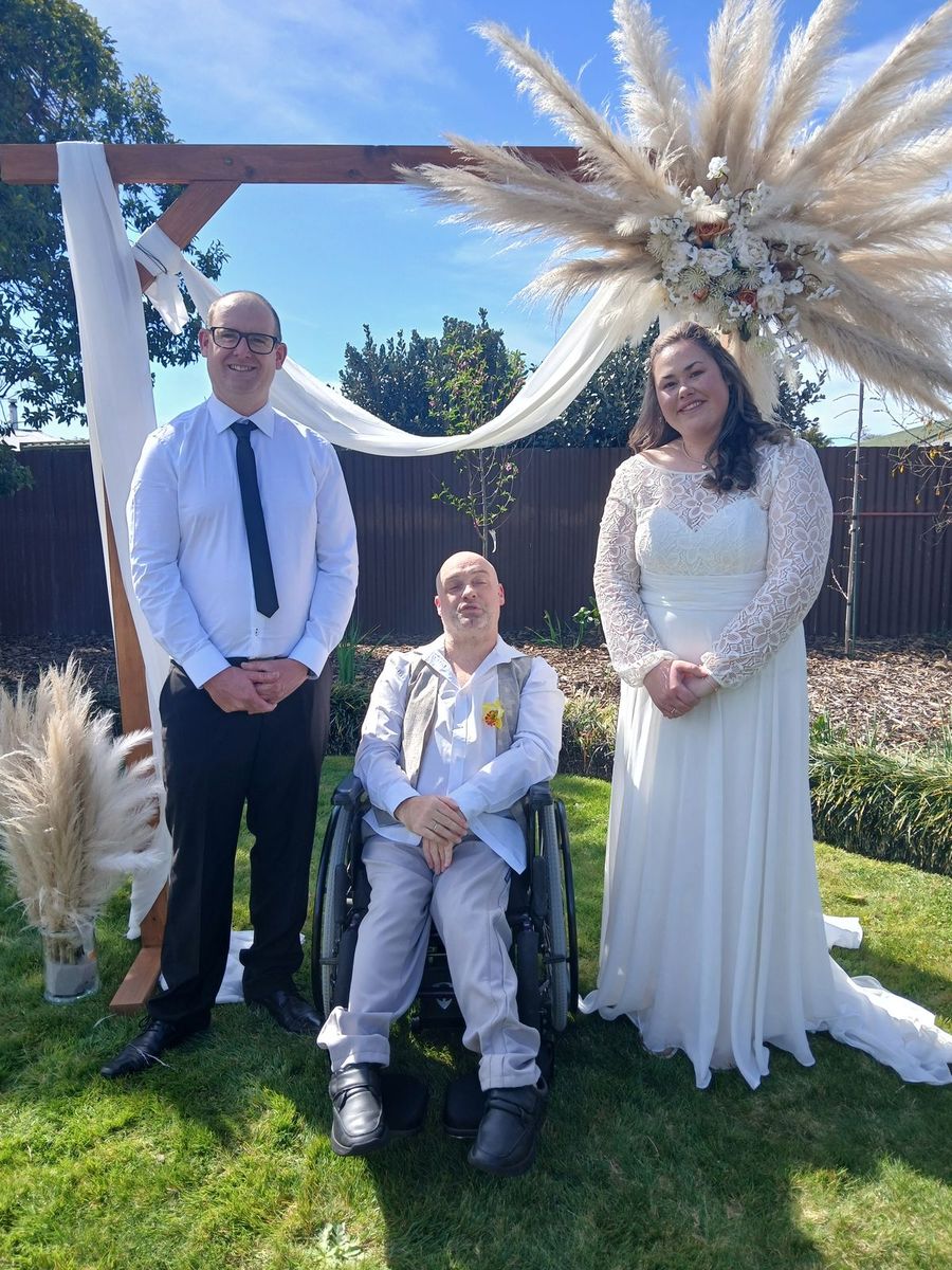 Gray with a bride and groom at a garden ceremony